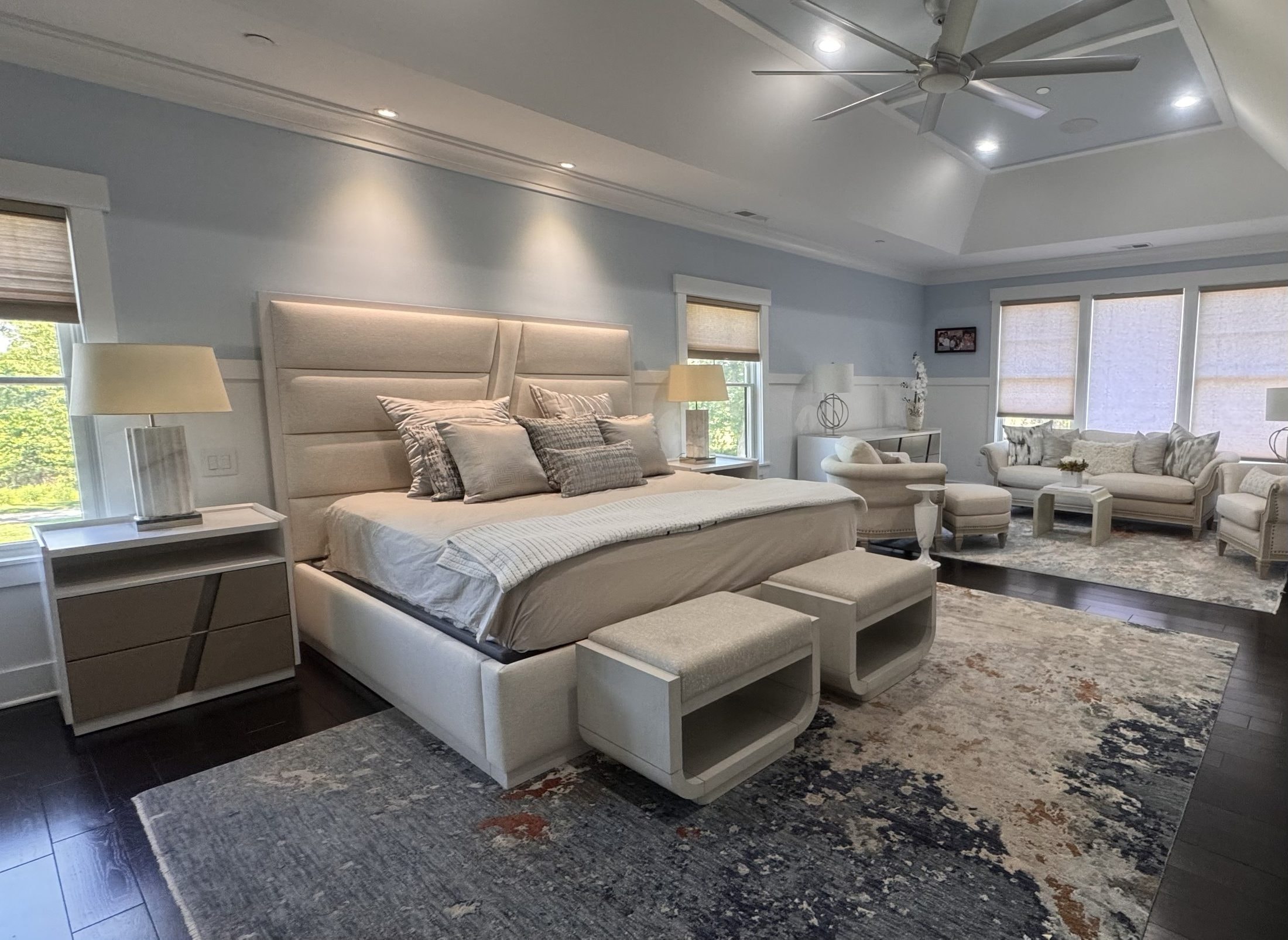 Primary Suite: channel-tufted bed, sitting area, layered rugs, designed and furnished by John Hashempour